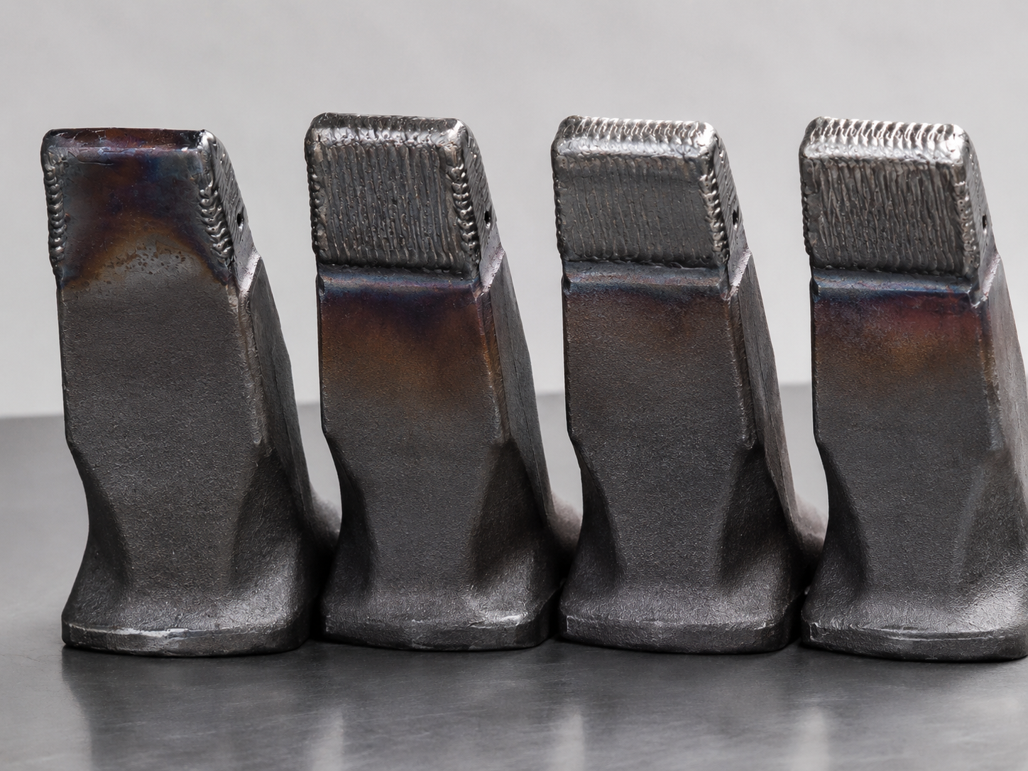 Gray hardfaced bucket teeth row