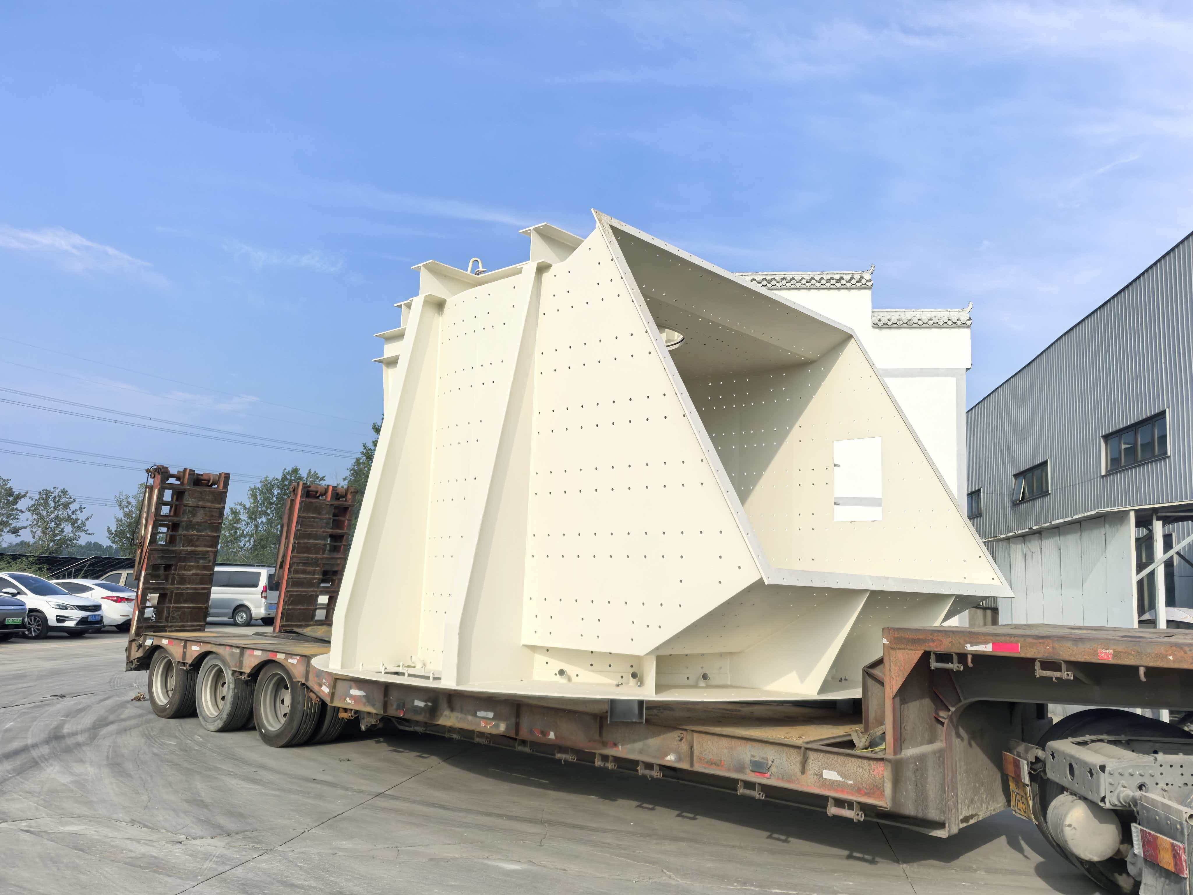 White mining feed hopper prepared on flatbed trailer